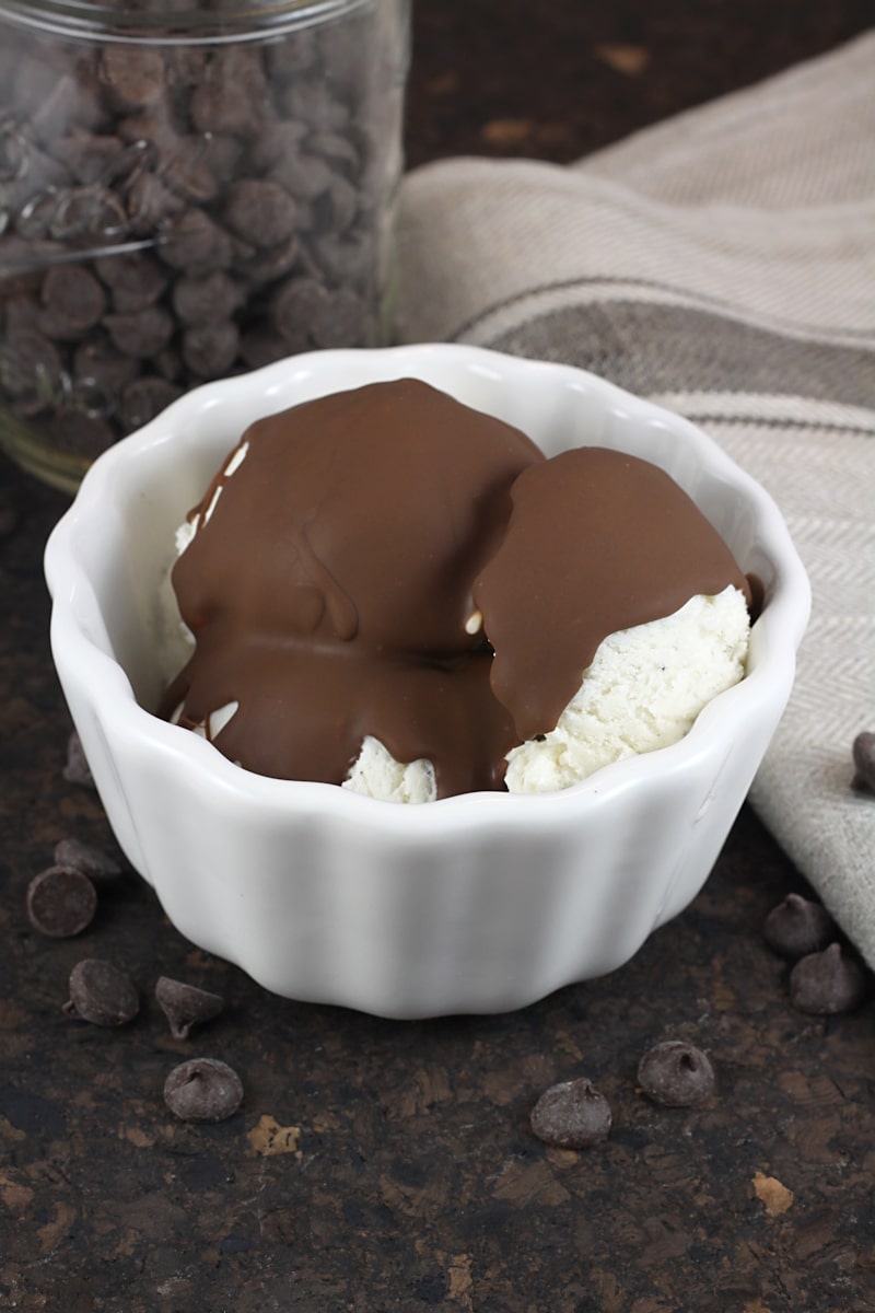 A bowl of vanilla ice cream topped with chocolate peanut butter magic shell.