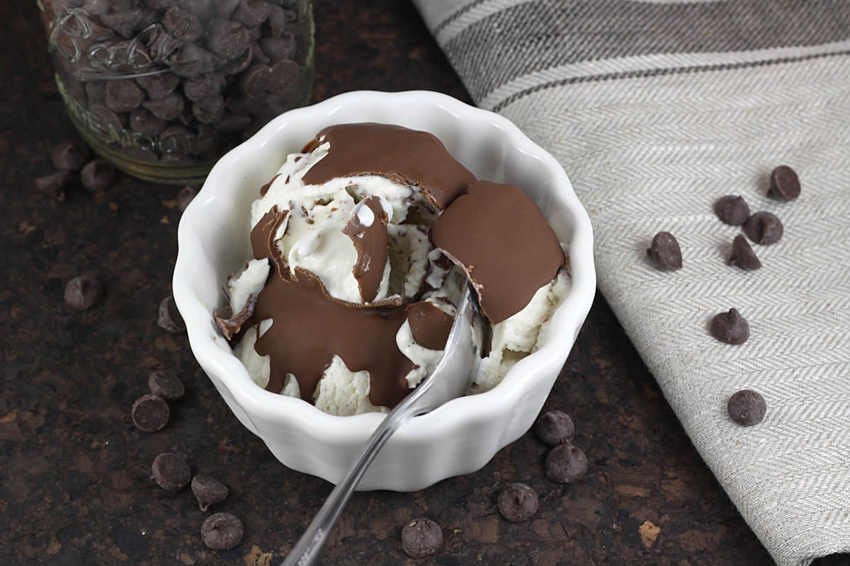 Chocolate peanut butter magic shell on vanilla ice cream that's been cracked open with a metal spoon