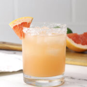 Lowball glass filled with pink grapefruit margarita with a salted rim.