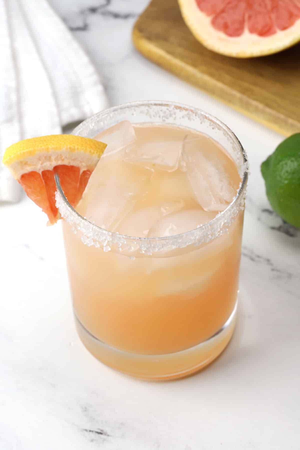 Overhead closeup view of a grapefruit margarita with a salted rim and wedge of grapefruit.