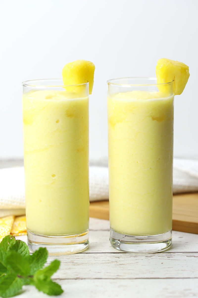 Two glasses of pineapple rum slush on a white counter top.