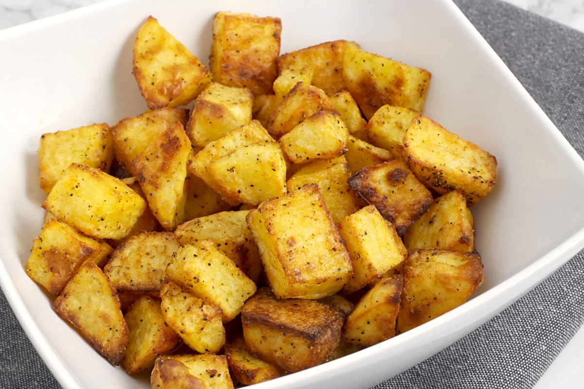 A white bowl filled with roasted potatoes.