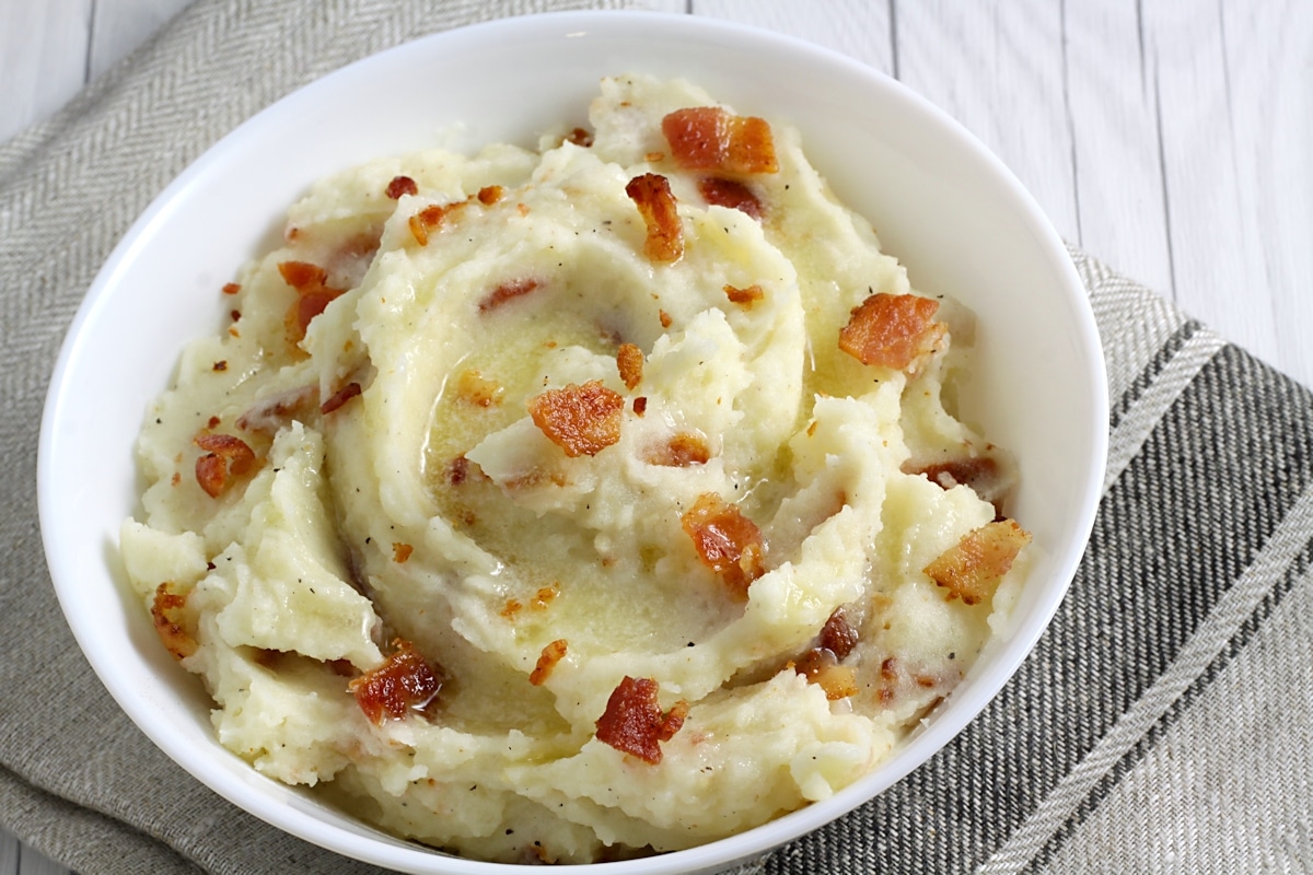 Bacon pieces on top of a bowl of mashed potatoes.