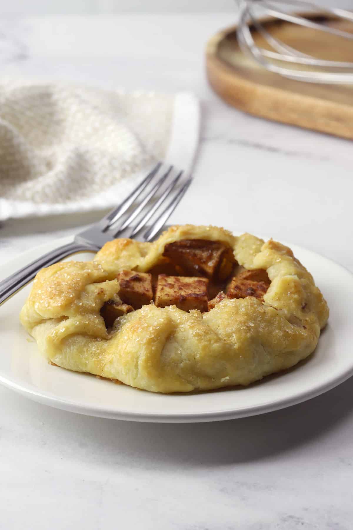 One mini apple galette on a plate with a fork.