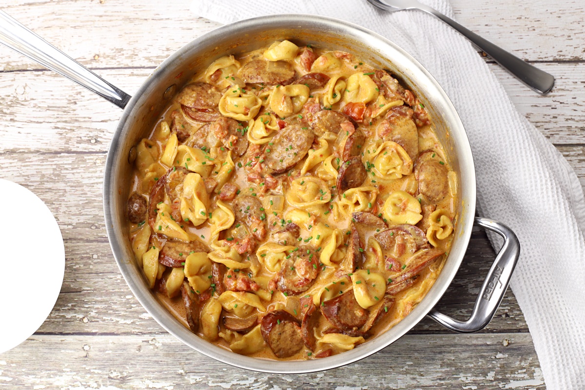 Saute pan filled with tortellini and sausage.