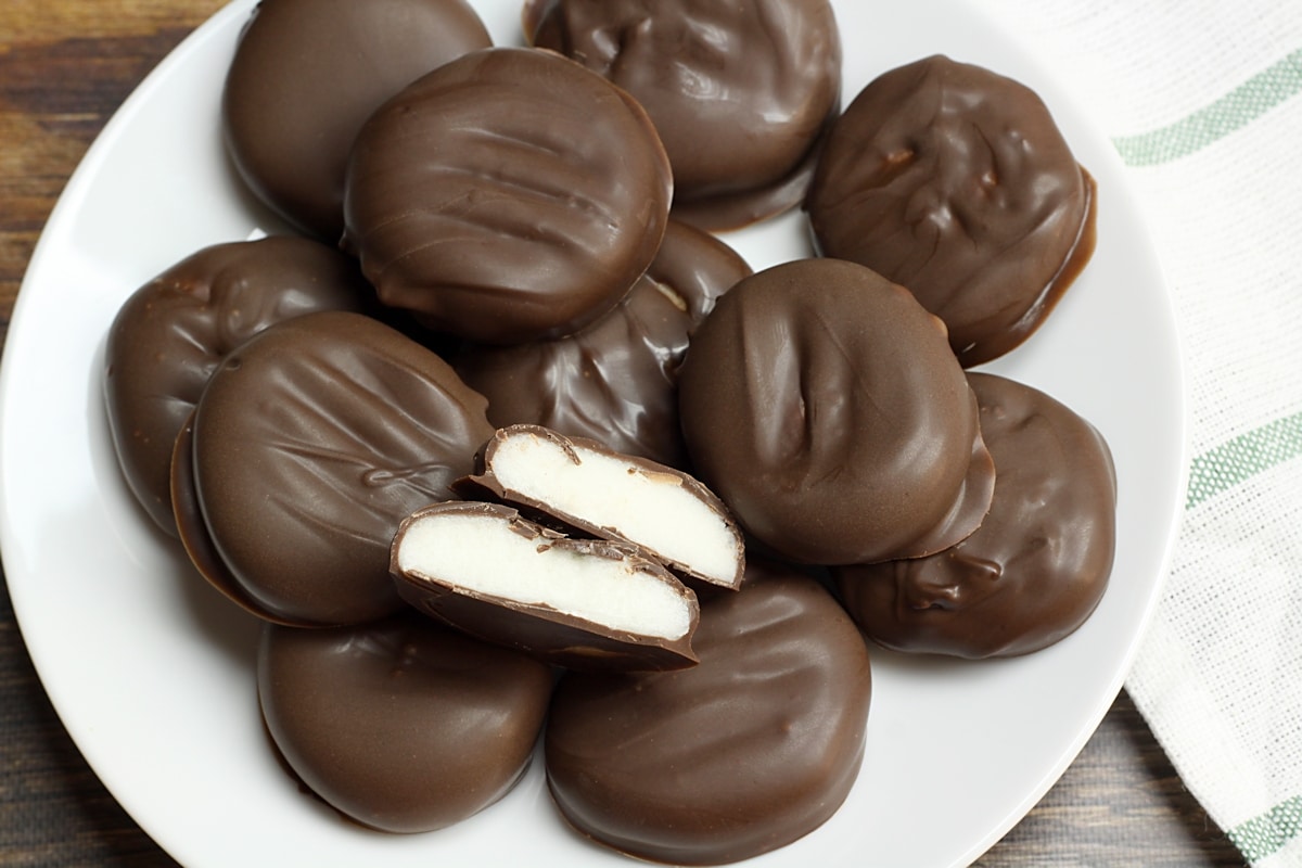 A plate of peppermint patties with one sliced in half to show the white filling.