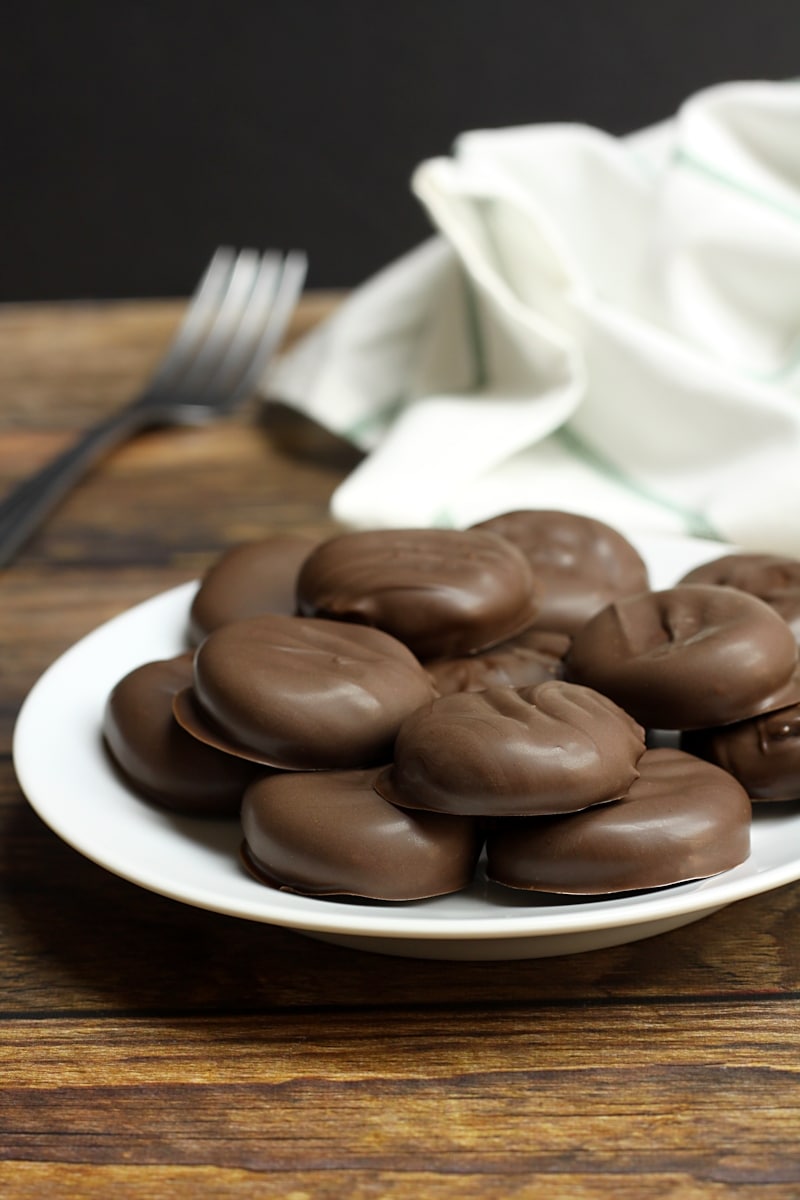 A white plate filled with stacked homemade peppermint patties.