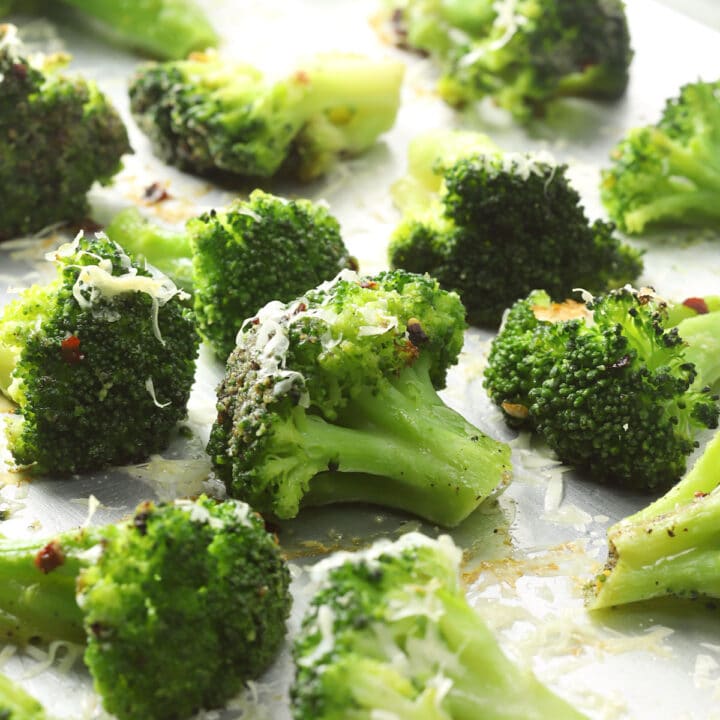 Roasted broccoli florets on a metal sheet pan.