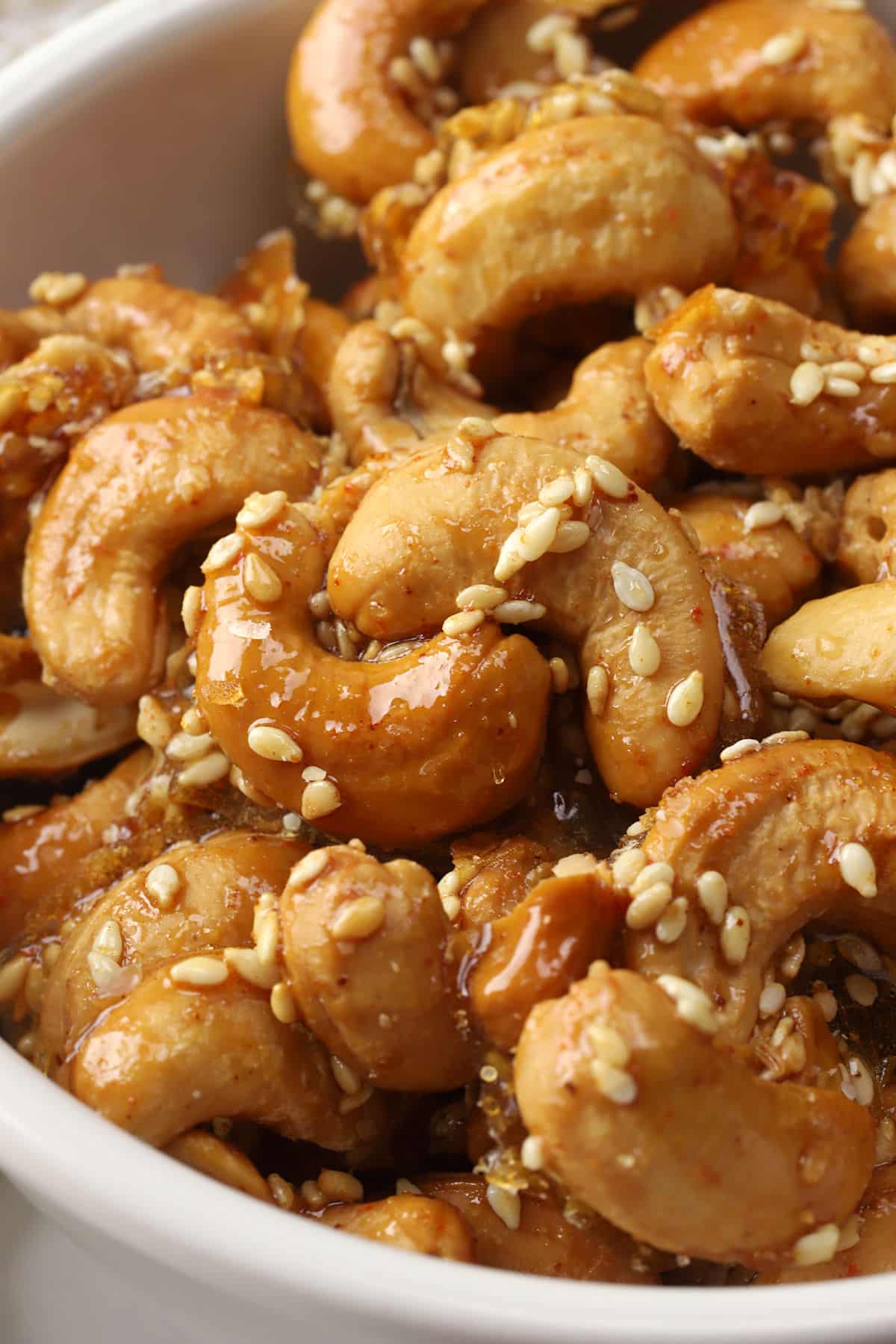 Close up of cashews coated in honey and sesame seeds.
