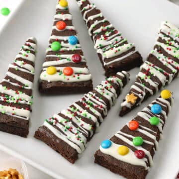 Square white plate filled with Christmas tree brownies.
