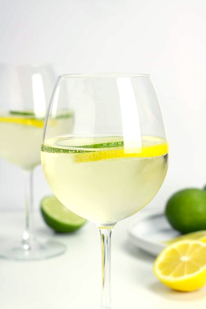 A wine glass filled with white wine with citrus slices.