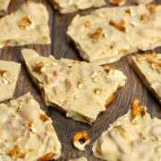 Pieces of peanut butter pretzel bark scattered on a wooden countertop.