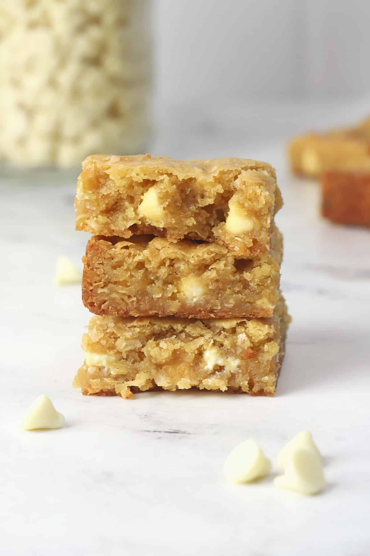Toasted coconut blondies stacked on a marble countertop.