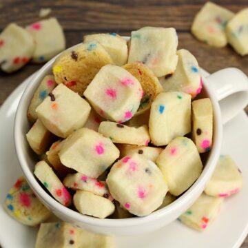 Shortbread cookies in a teacup with rainbow sprinkles.