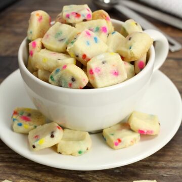 A teacup filled with tiny shortbread cookies.