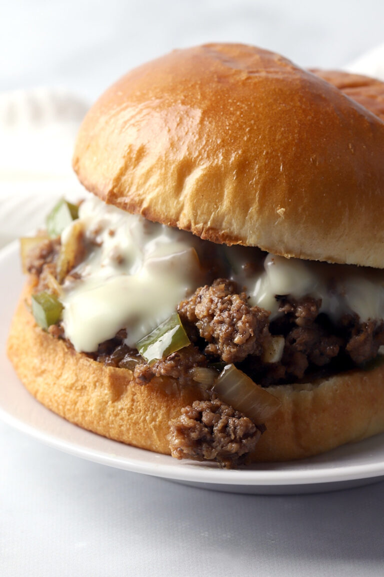 Close up of ground beef, onions, and bell pepper in a sloppy joe sandwich.