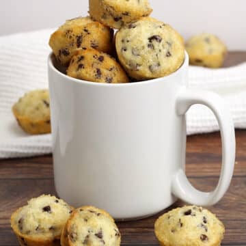 A white coffee mug filled with mini muffins.