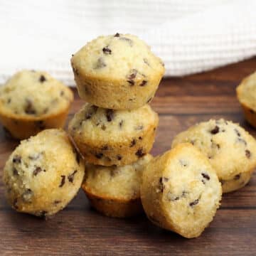 Chocolate chip mini muffins stacked on a wood counter top.