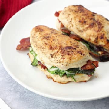 Two bacon spinach stuffed chicken breasts on a serving plate.