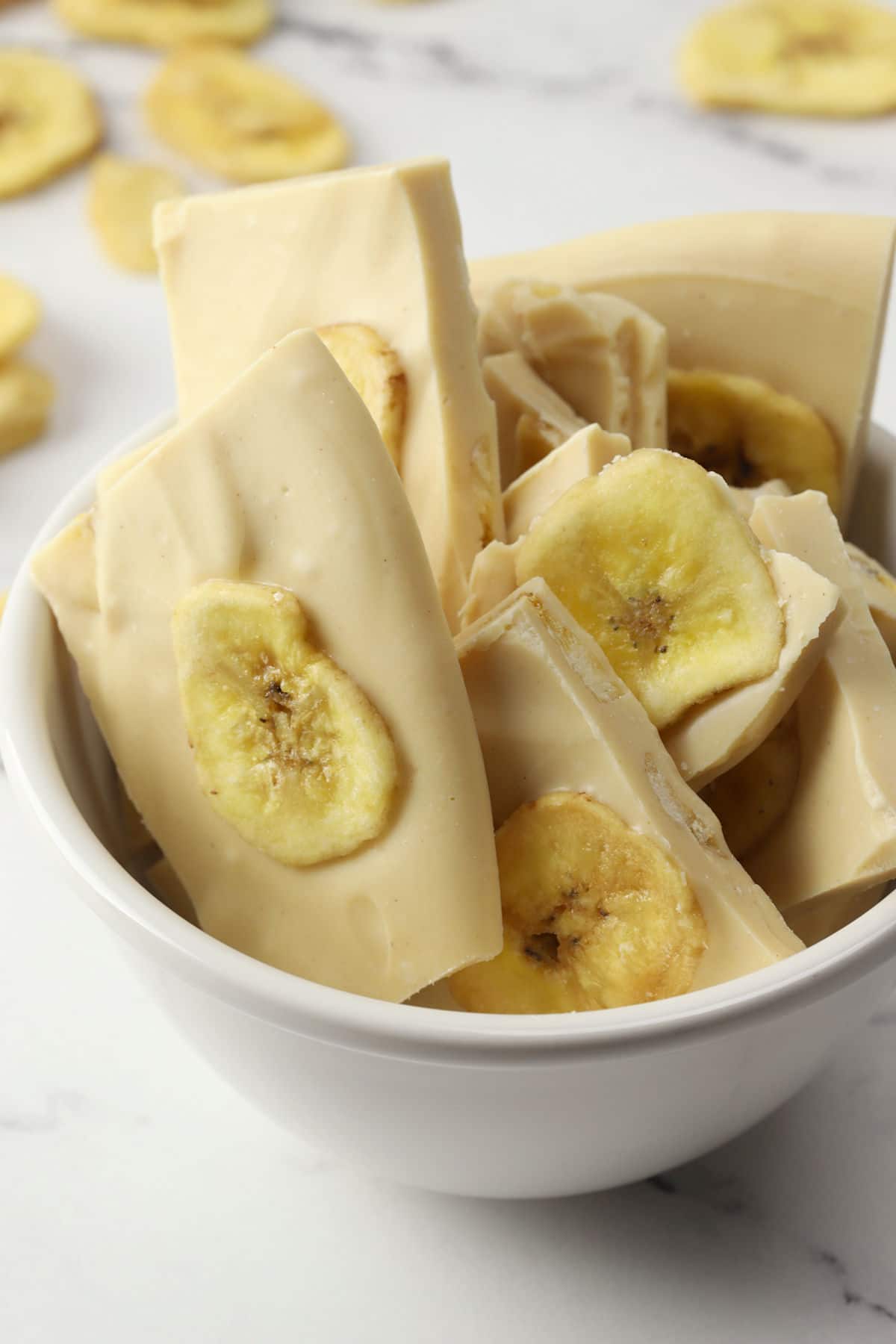 Small white bowl filled with pieces of peanut butter banana chip bark.
