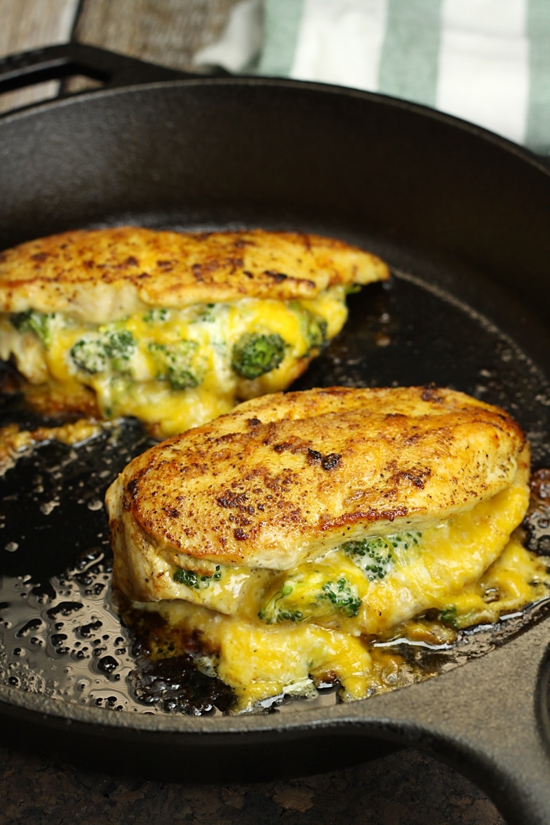 Chicken breasts in a cast iron pan stuffed with broccoli and cheese.