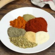 A white plate with a variety of spices and herbs.