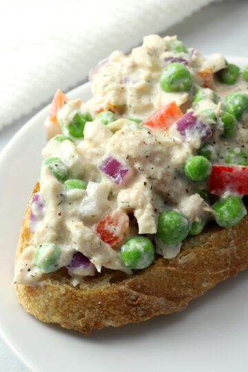 Tuna salad with peas served open faced on a slice of bread.