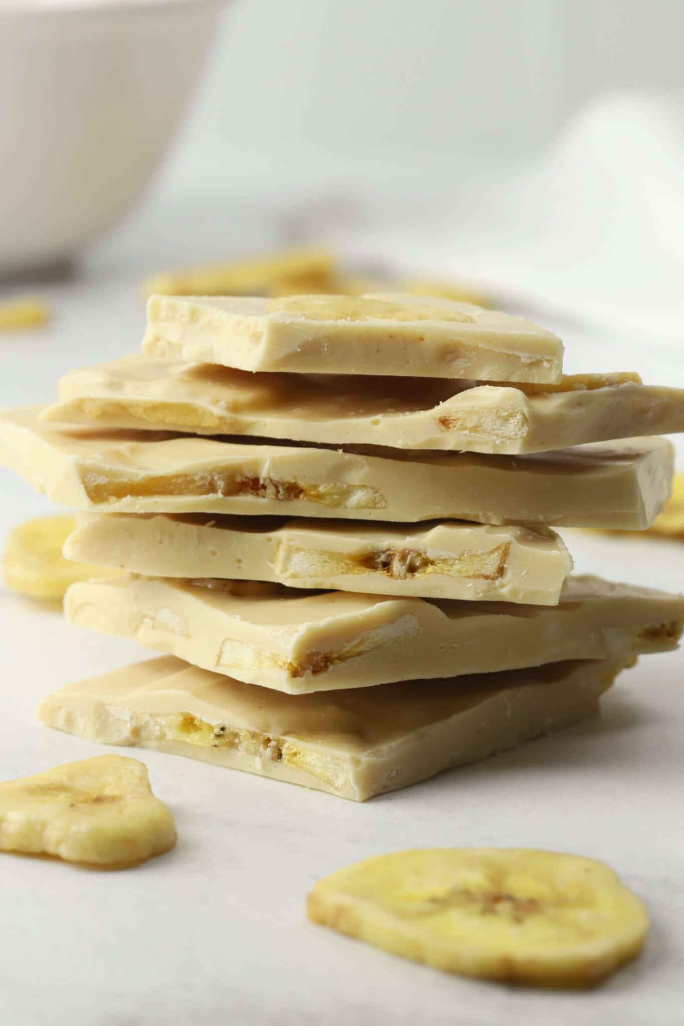 Pieces of banana chip candy bark stacked on a counter top.