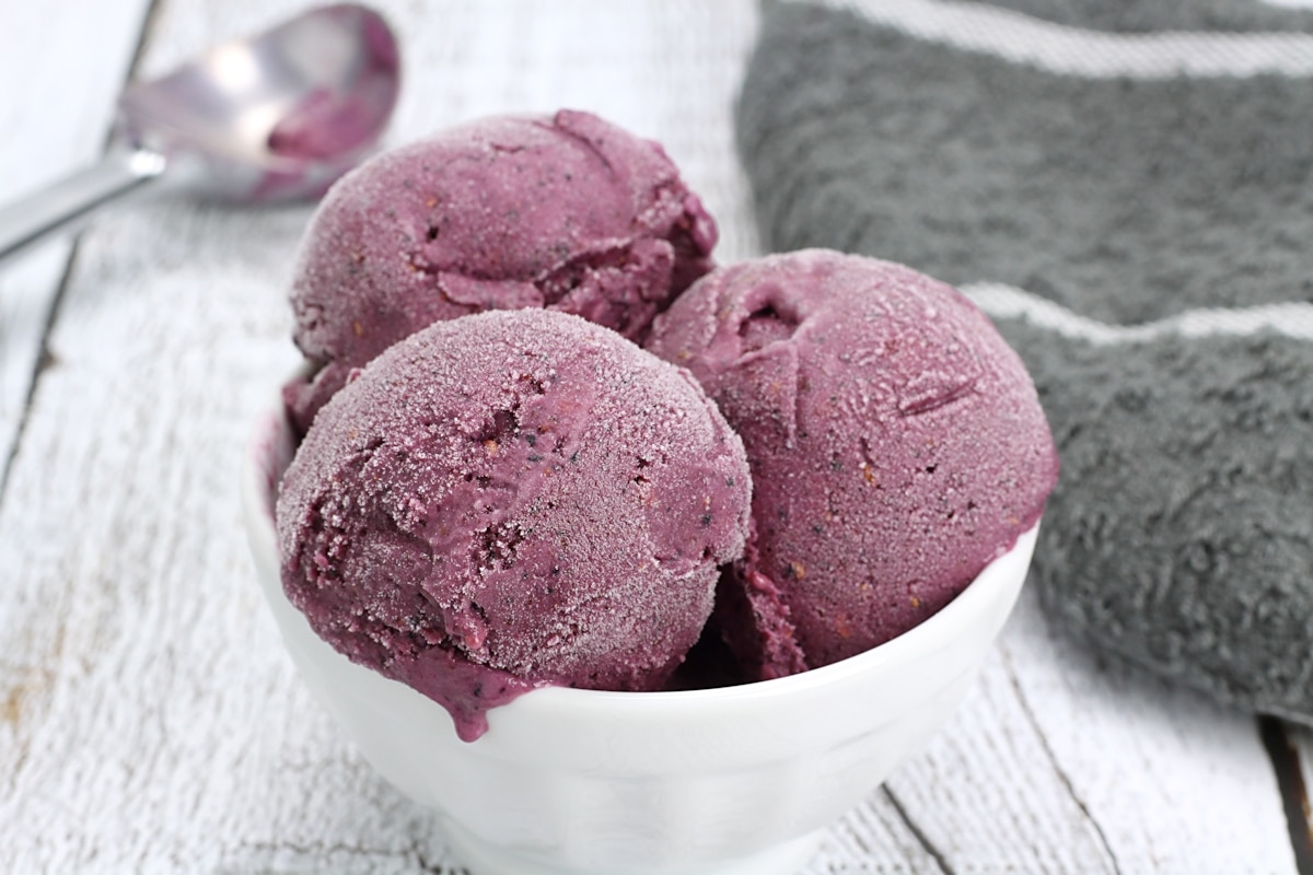 A white bowl with three scoops of purple sherbet.