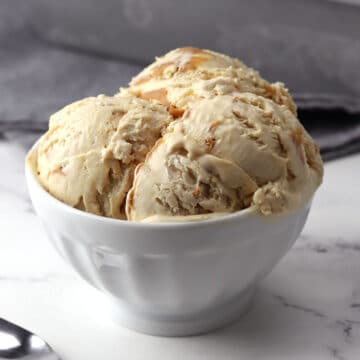 A white serving bowl filled with scoops of peanut butter ice cream.