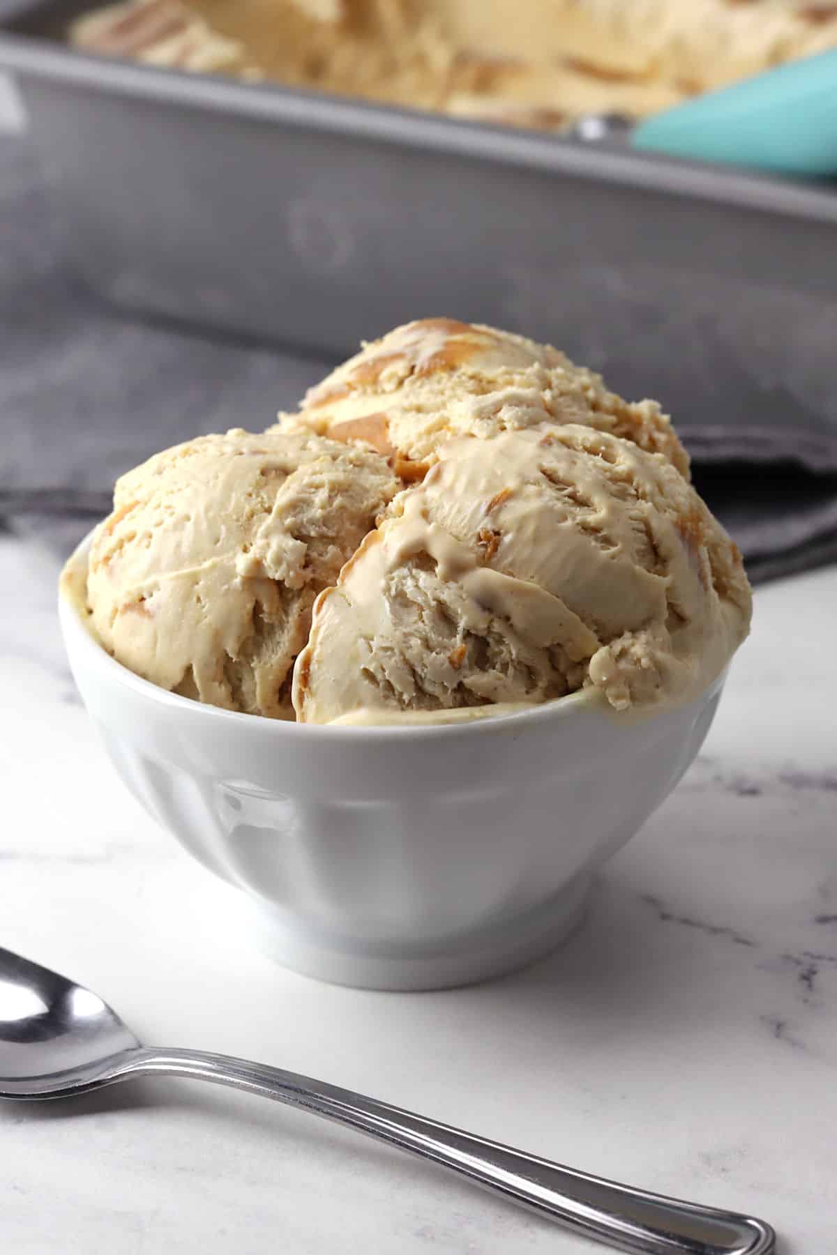 A white serving bowl filled with scoops of peanut butter ice cream.
