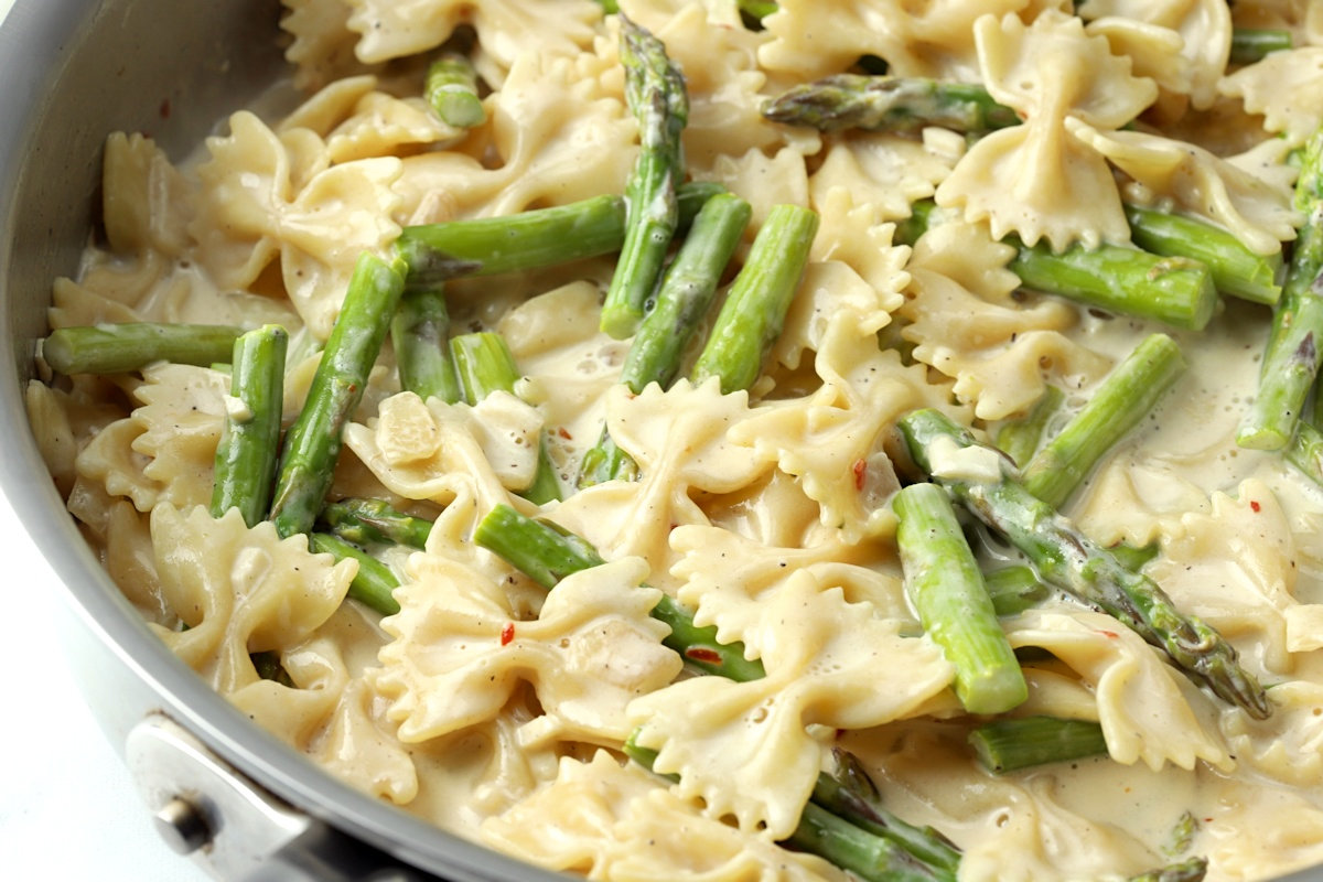 A creamy sauce coats bow tie pasta and asparagus.