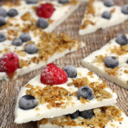 Frozen yogurt bark topped with berries and granola on a counter top.