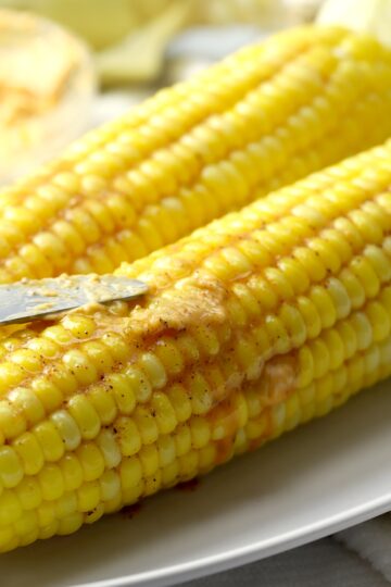 Spreading butter on an ear of corn.