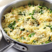 A sauté pan filled with spaghetti squash and kale topped with parmesan cheese.