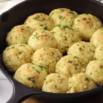 A cast iron skillet filled with baked cheese stuffed biscuits.