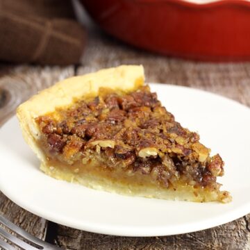 Slice of pecan pie on a white plate.