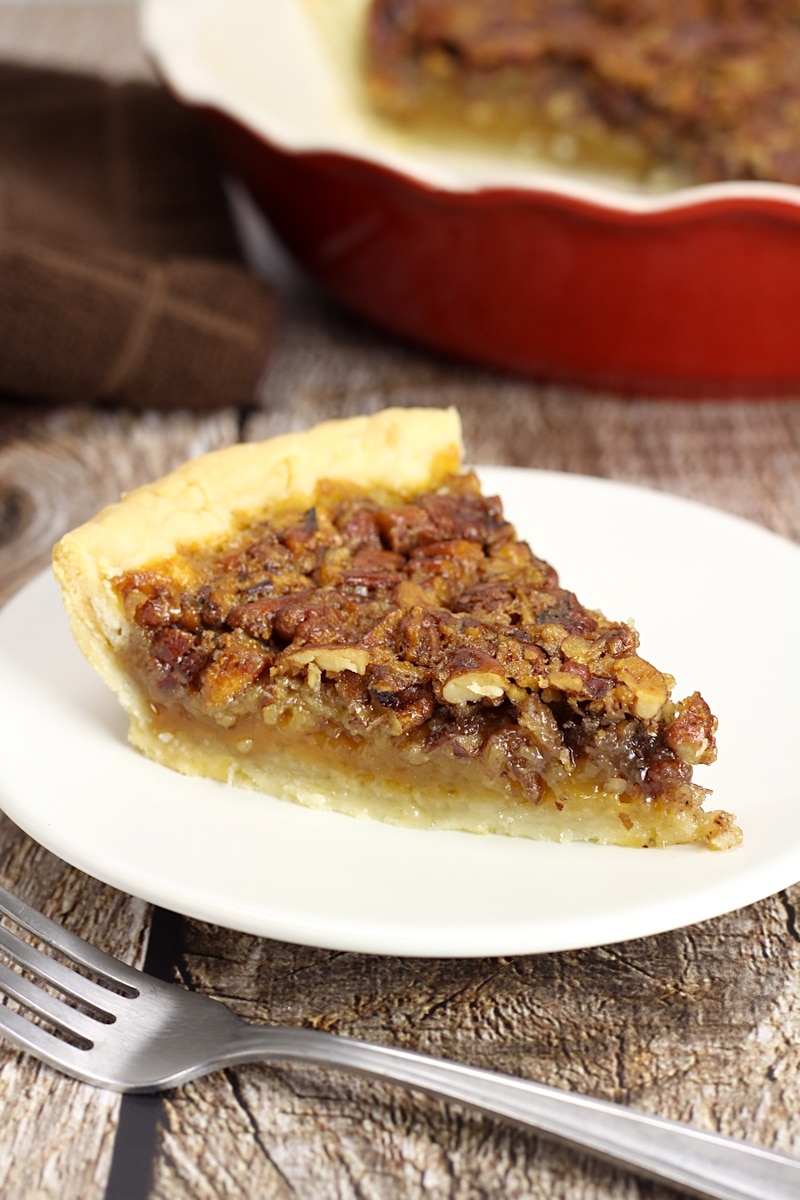 Slice of pecan pie on a white plate.