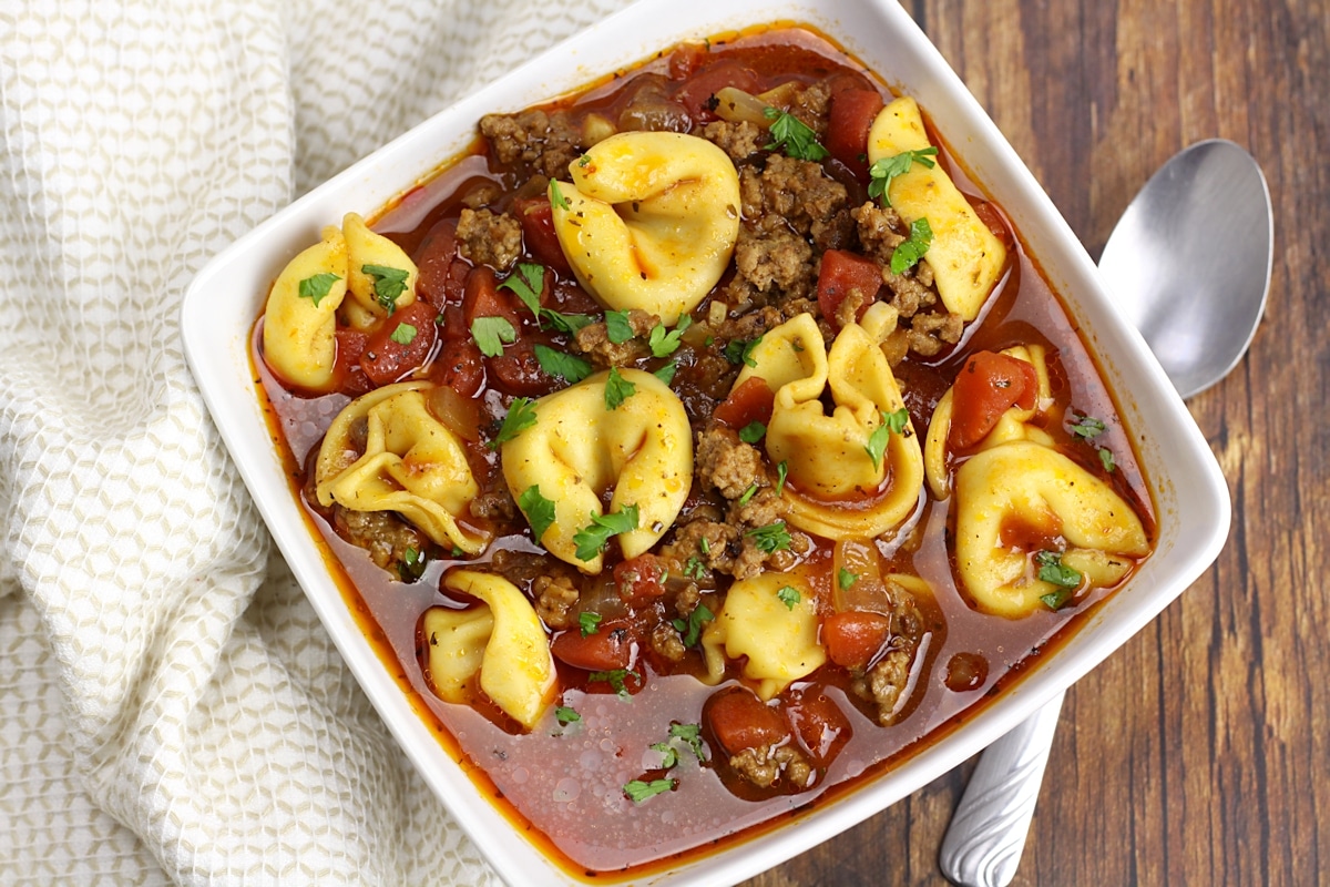 Square soup bowl filled with tortellini and beef.