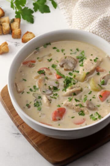 A white bowl filled with creamy chicken mushroom soup.