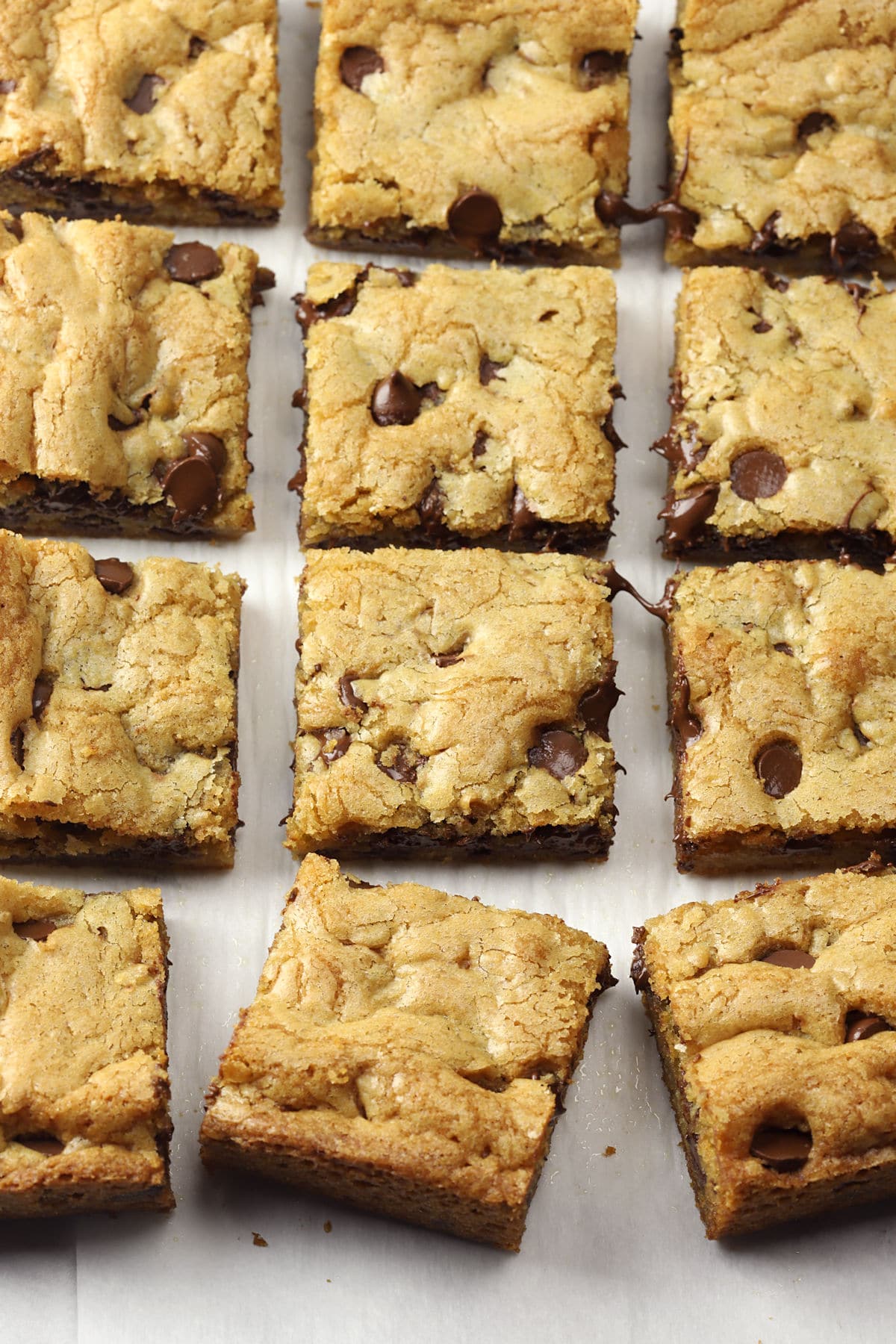 Cookie bars sliced into squares on a sheet of parchment paper.