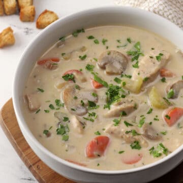 A white bowl filled with creamy chicken mushroom soup.
