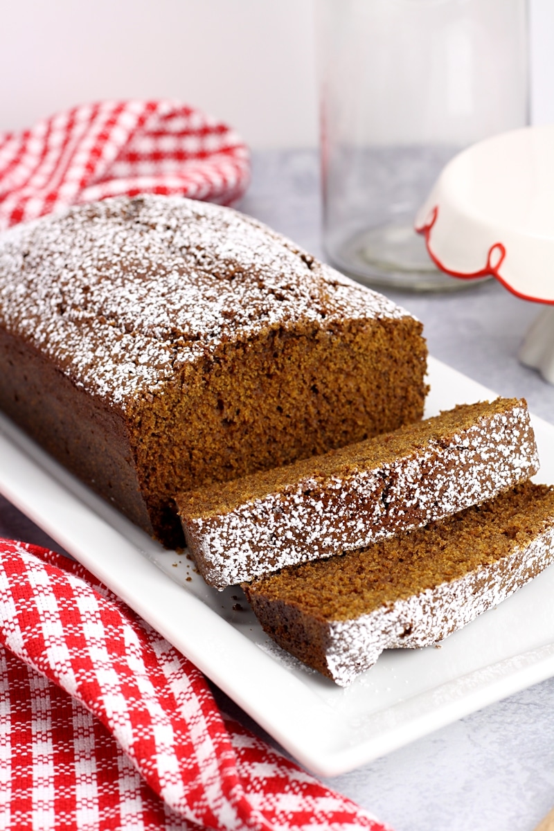 A serving plate of gingerbread with a red checked towel.
