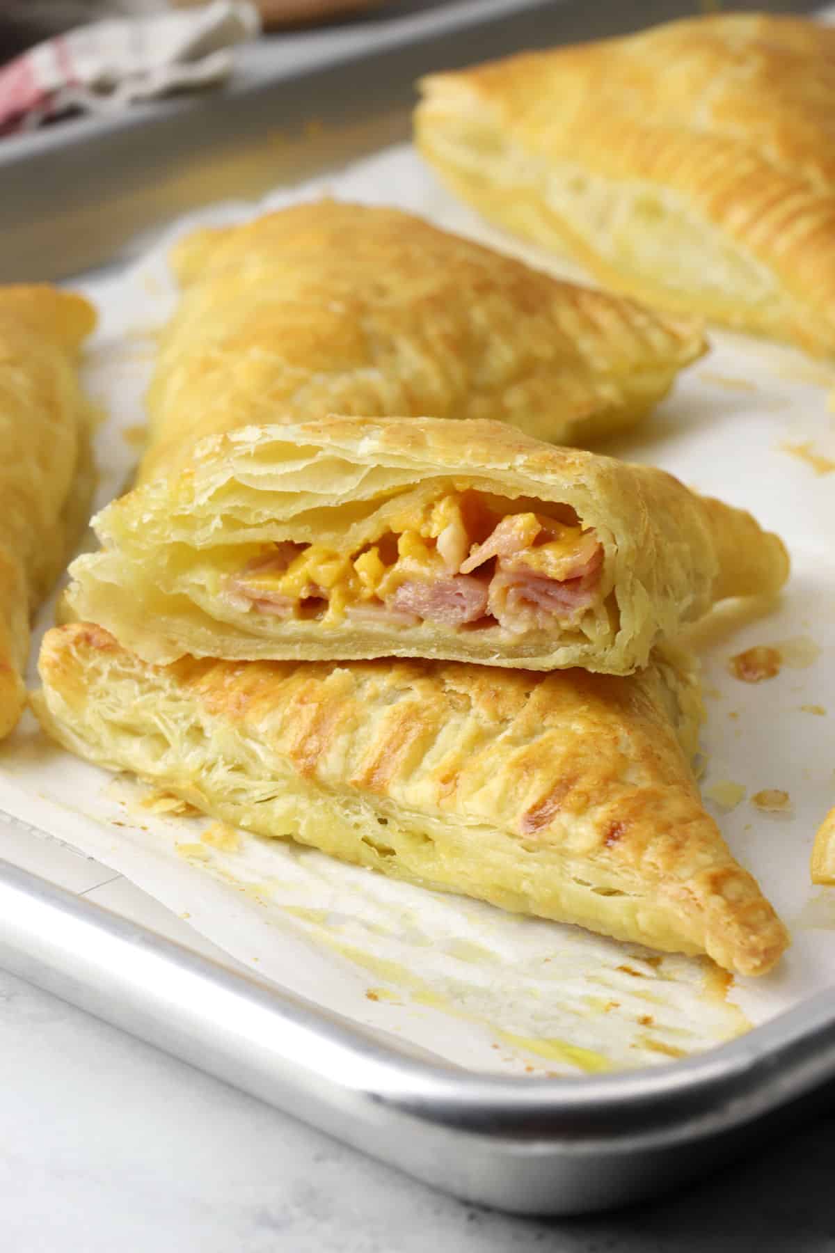 Ham and cheese puff pastry turnover sliced in half to show filling.
