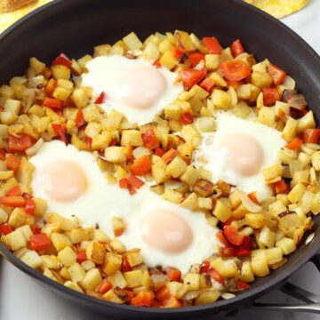 Sunny side up eggs nestled in a skillet of hash browns.