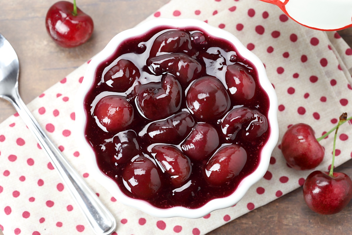 From above, a bowl of cherries with a polka dot towel.