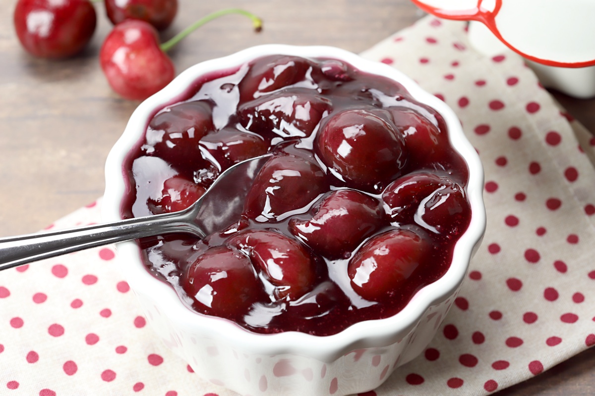 A spoon scooping into a bowl of cherry pie filling.