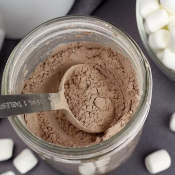 A metal spoon in a jar of hot chocolate mix.