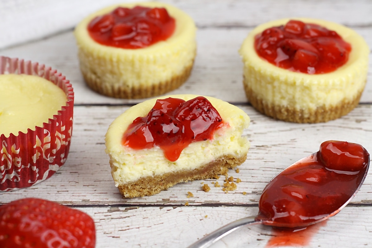 A cheesecake sliced in half with strawberry topping dripping down.