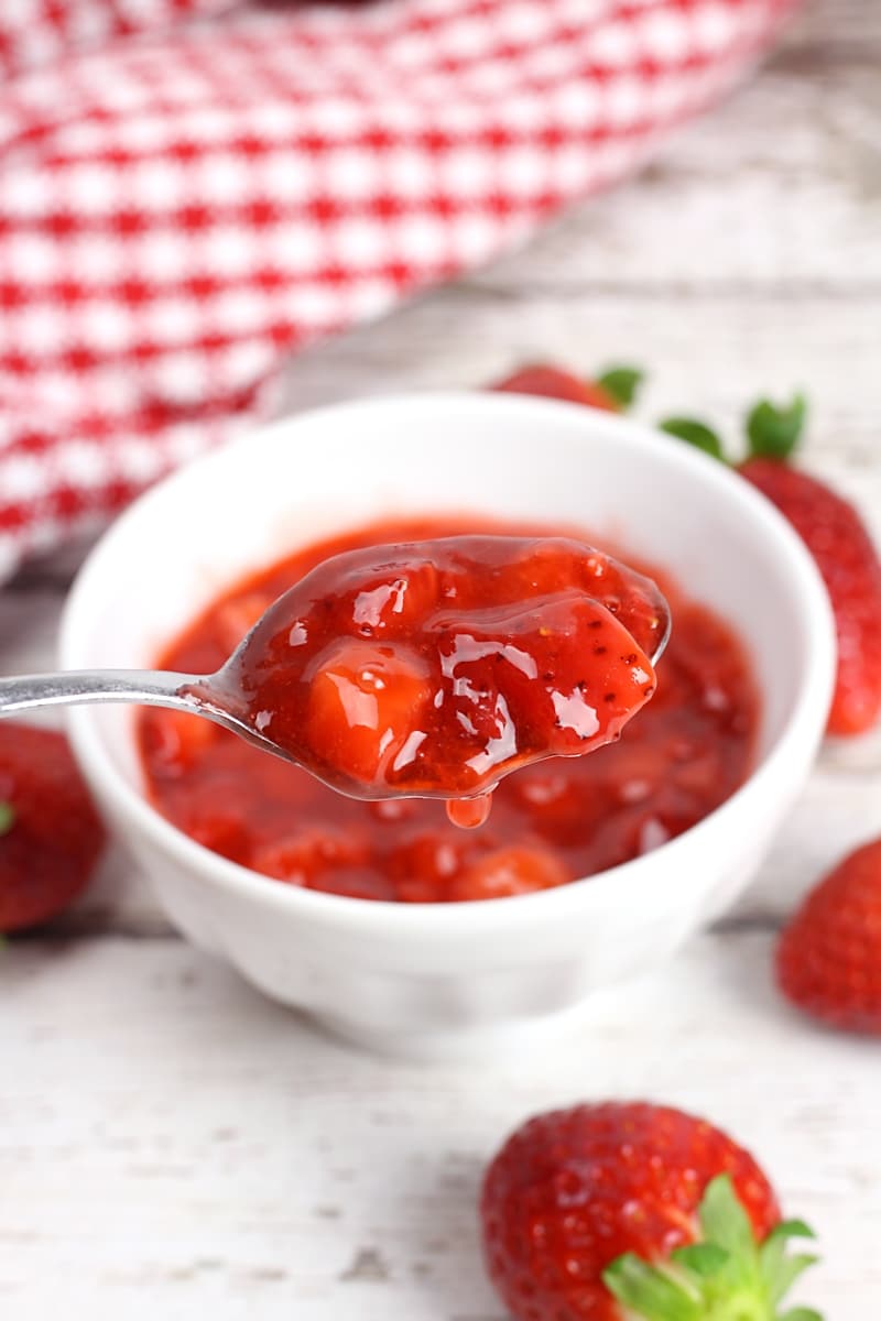 A metal spoon filled with strawberries.